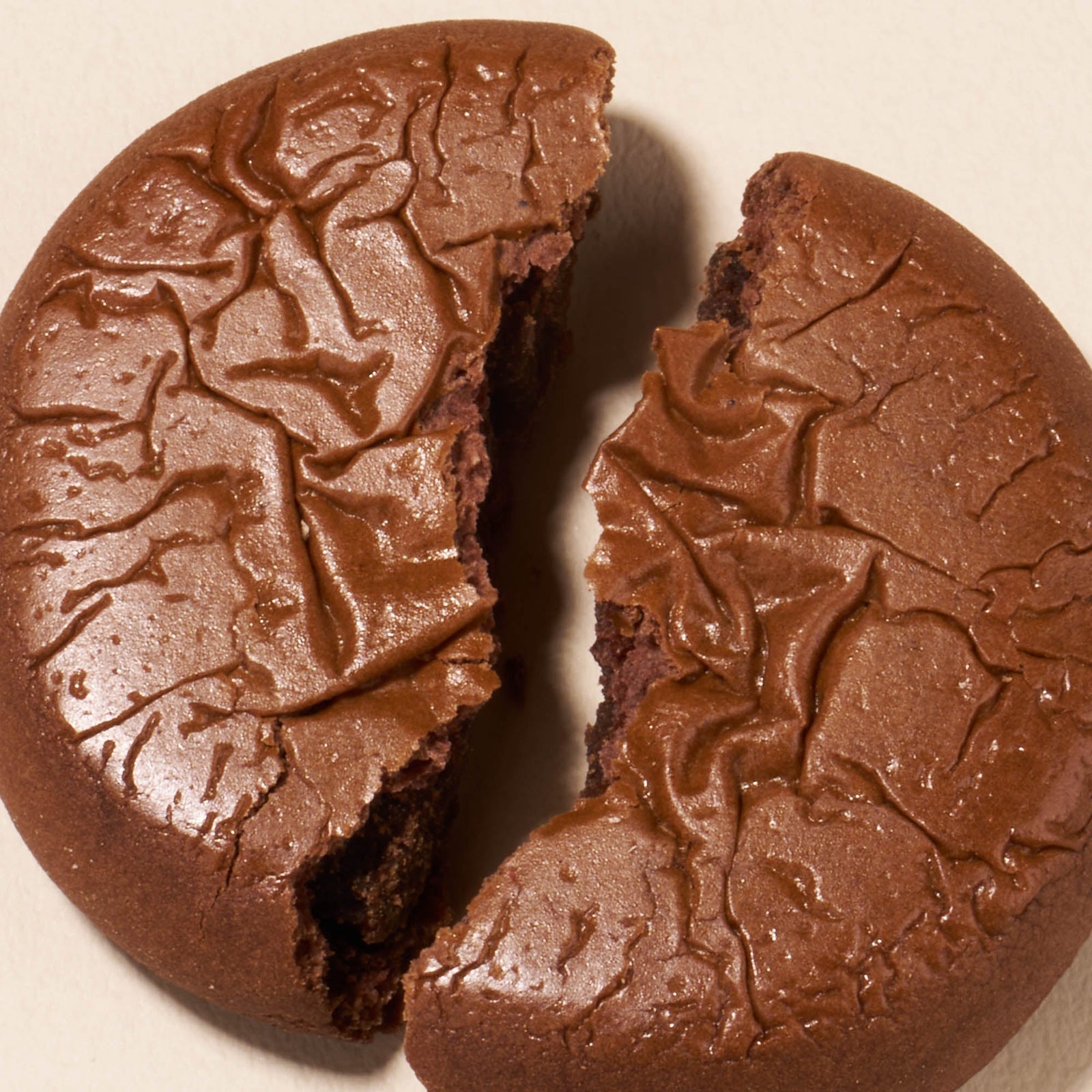 A round chocolate cookie with a cracked surface is split in half on a light background, similar to the sweets found in the Bokksu Snack Box: Seasons of Japan.