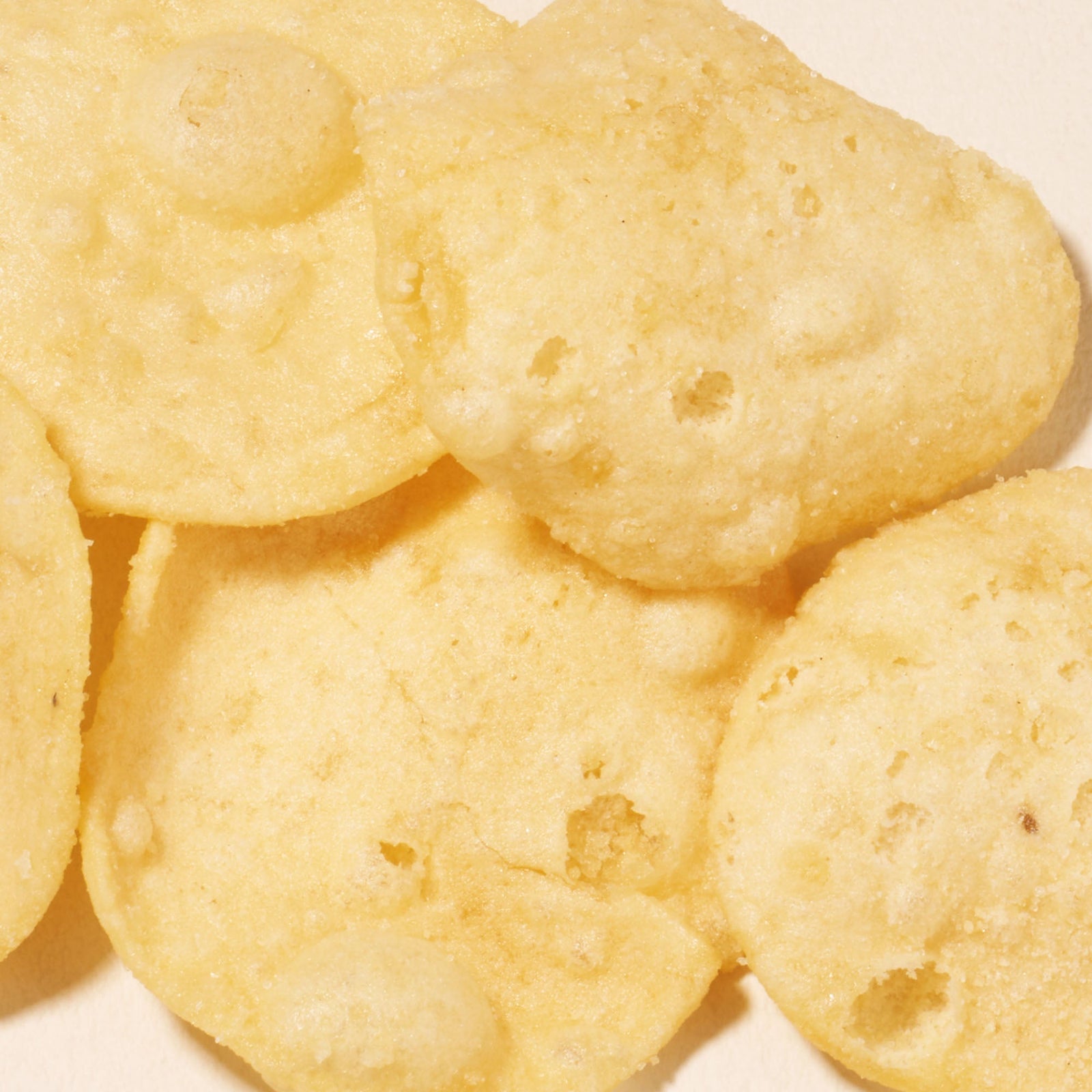 Close-up of several round, light yellow papad chips with a bubbly, crispy texture—perfect for enjoying as part of your Bokksu Snack Box: Seasons of Japan or adding to your Japanese snacks collection.